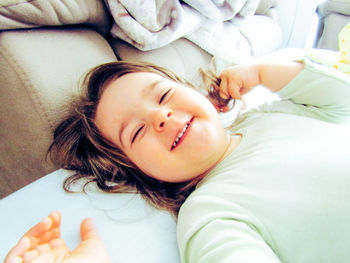 High angle view of smiling girl lying on bed at home