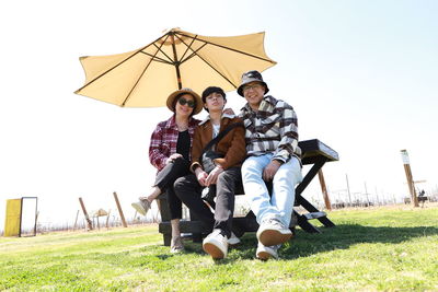 Friends sitting posing for photo under an umbrella