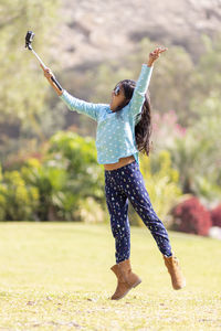 Full length of woman with arms raised on field