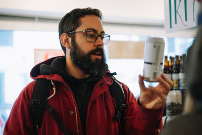 Portrait of man wearing eyeglasses holding beer