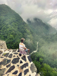 Rear view of boy on mountain against sky