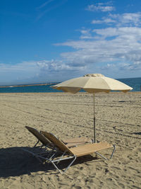 Chairs on beach by sea against sky