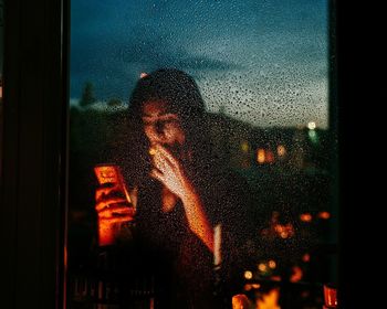 Portrait of man seen through wet glass window