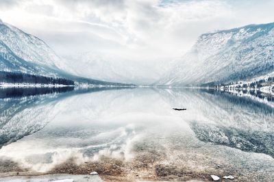 Scenic view of lake by snowcapped mountains against sky