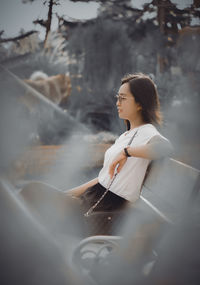 Portrait of young woman looking away while standing outdoors