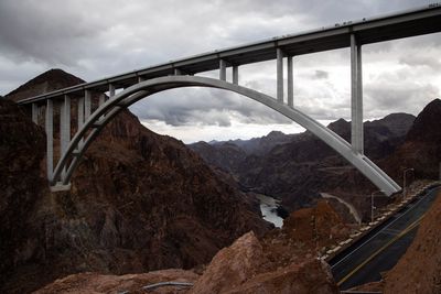 Arch bridge over mountains against sky