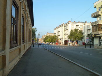 Street amidst buildings against clear blue sky