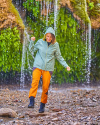 Portrait of smiling young woman standing on street during rainy season