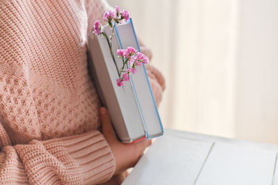 A girl with books and pink flowers, crop view. spring  blogger content, reading and back to school.