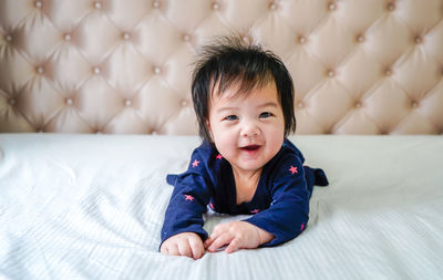 Cute little caucasian baby lying on bed at home. looking and smiling at camera.