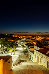 High angle view of illuminated buildings in city against clear blue sky