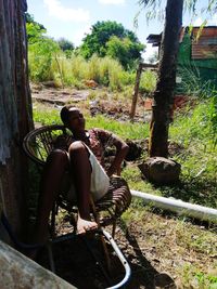 Rear view of shirtless man sitting on land