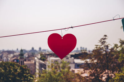 Close-up of red heart shape against built structure against sky