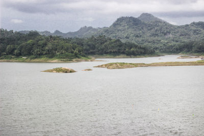 Scenic view of river by mountains against sky