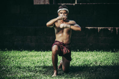 Full length of shirtless man standing on grass