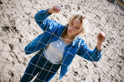 Young woman standing by net