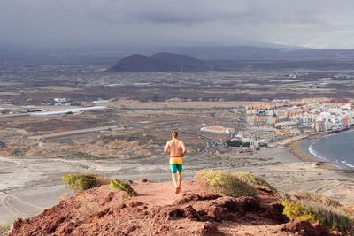 Rear view of shirtless man running on landscape