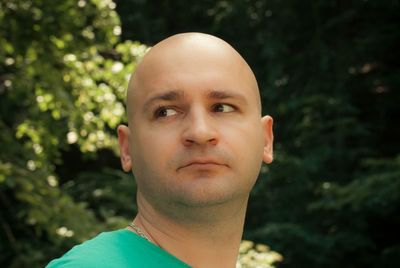 Close-up of bald man looking away in forest