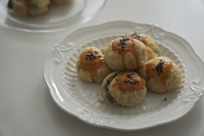 There are some delicious black sesame egg yolk pastries freshly baked on the plate on the table