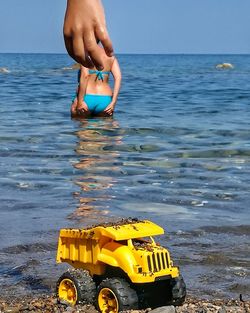 Full length of hand on yellow sea against sky