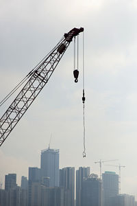Crane by building against sky