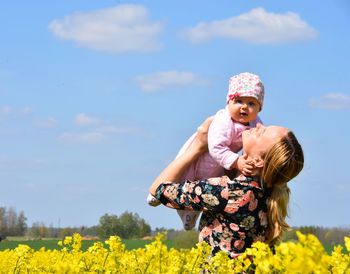 Mom and daughter in rapeseed blooming field