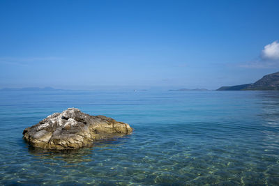 Rock formation in sea against blue sky