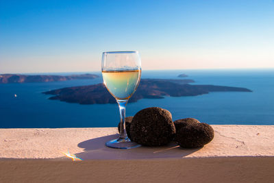 Wineglass against clear blue sky on sea