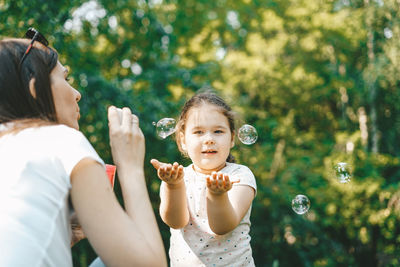 Mother and daughter holding baby girl outdoors