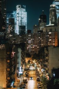 Illuminated street amidst buildings in city at night