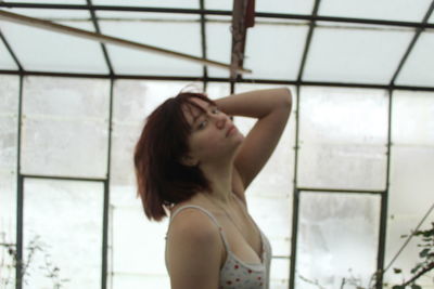 Portrait of young woman looking through window