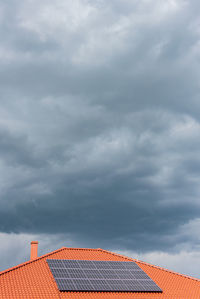 Red tile roof with photovoltaic panels during stormy weather solar pv installation and dark blue sky