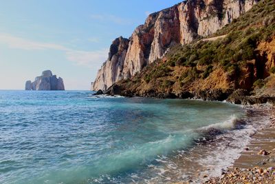 Rock formation by sea against sky