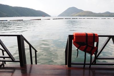 Chairs and table by lake against sky