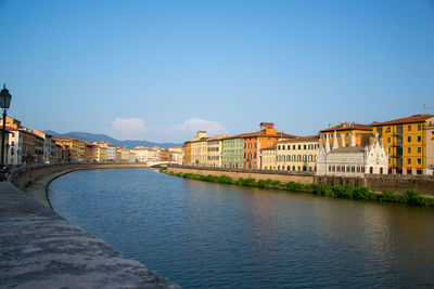 River by buildings against blue sky