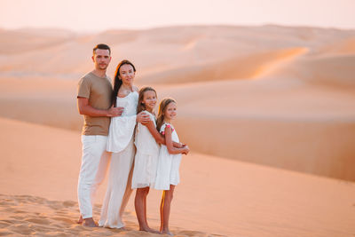 Portrait of family standing on sand dunes at desert