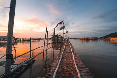 Pier over lake against sky during sunset