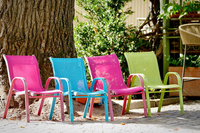 Empty chairs and table by sidewalk cafe against trees