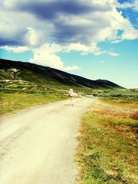 Road passing through landscape against cloudy sky