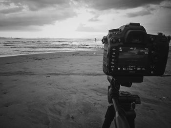 View of camera on beach against cloudy sky