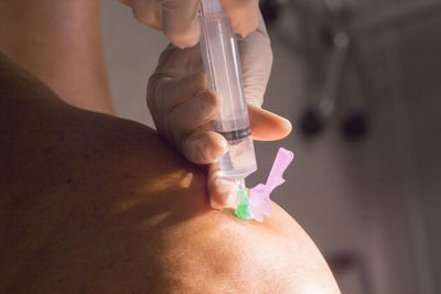 Close-up of doctor injecting patient on knee