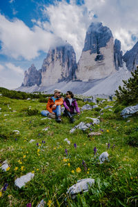 People sitting on mountain against sky