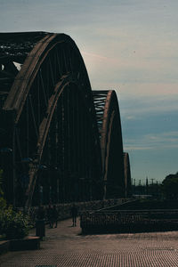 Rear view of people walking on bridge against sky