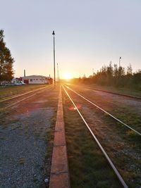 Railroad tracks against sky during sunset