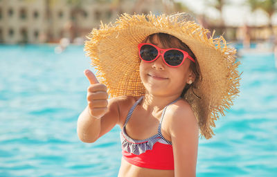 Portrait of young woman wearing sunglasses while swimming in pool