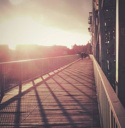 People walking on footbridge at sunset