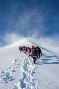 View of people on snowcapped mountain against sky