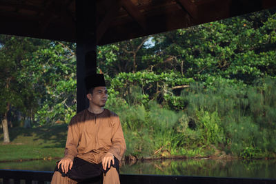 Portrait of young man standing against plants