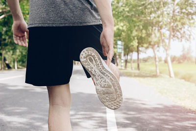 Low section of man stretching on road