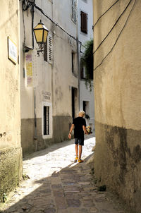 Rear view of woman walking on walkway in city